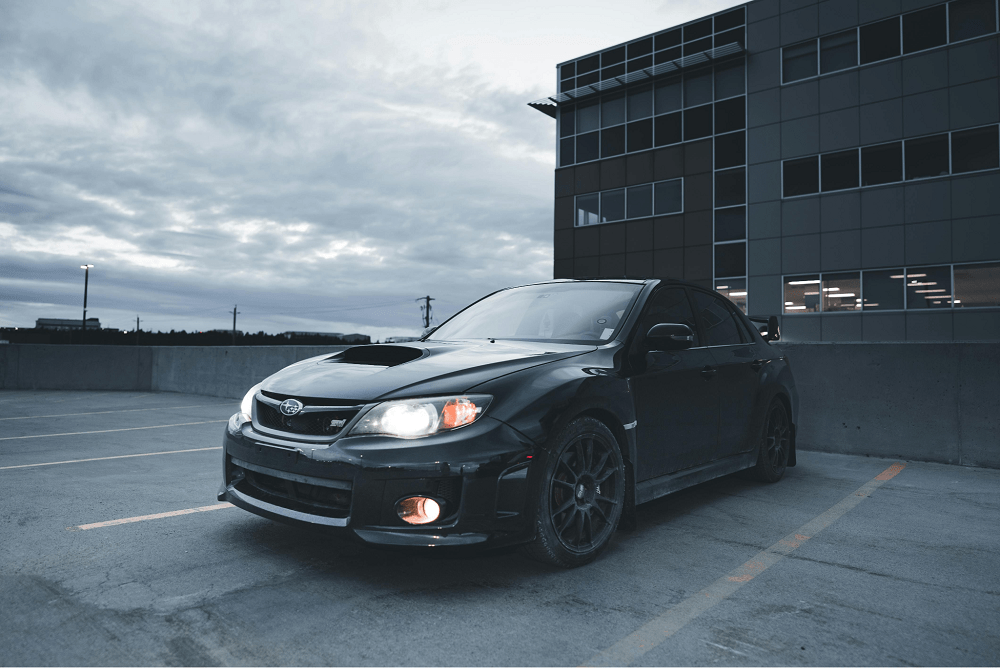 A black Subaru parked in a parking lot